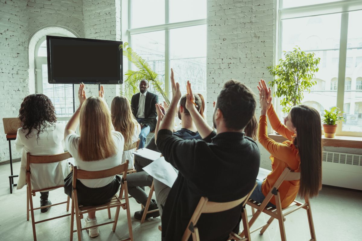 Enthusiastic participants in media training raise their hands from their chairs