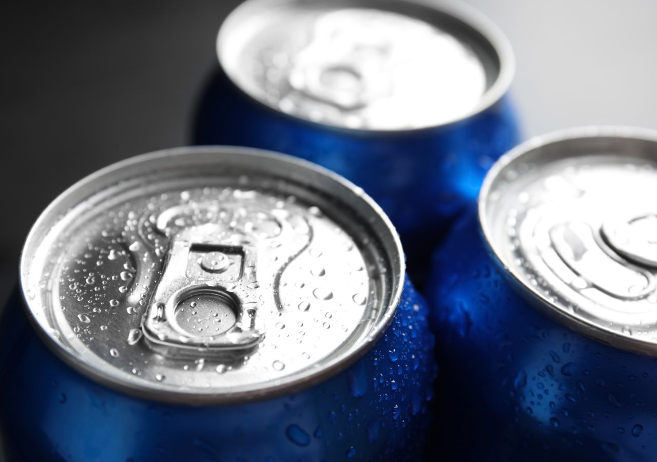 Tops of blue soda cans covered in condensation