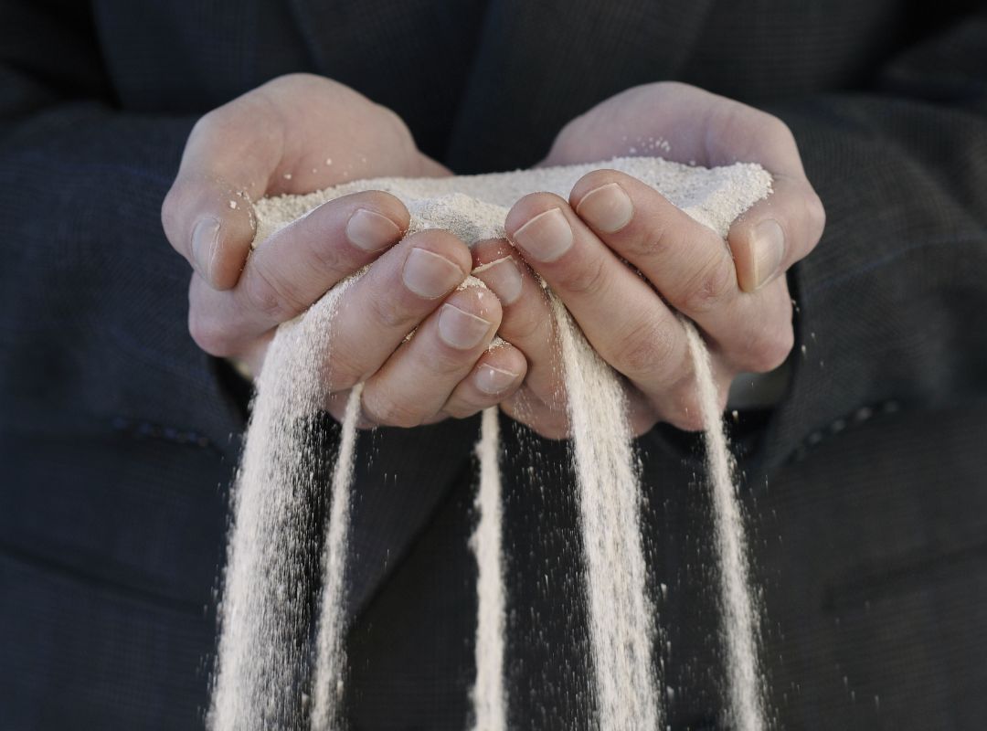 Sand slippling through the fingers of a man carrying sand in cupped hands