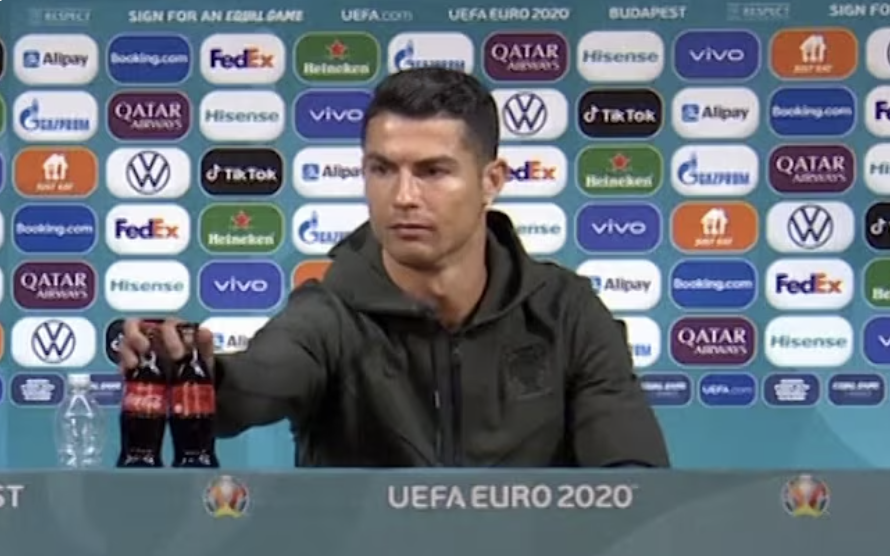 Cristiano Ronaldo grabbing two Coke bottles from the table at a press conference